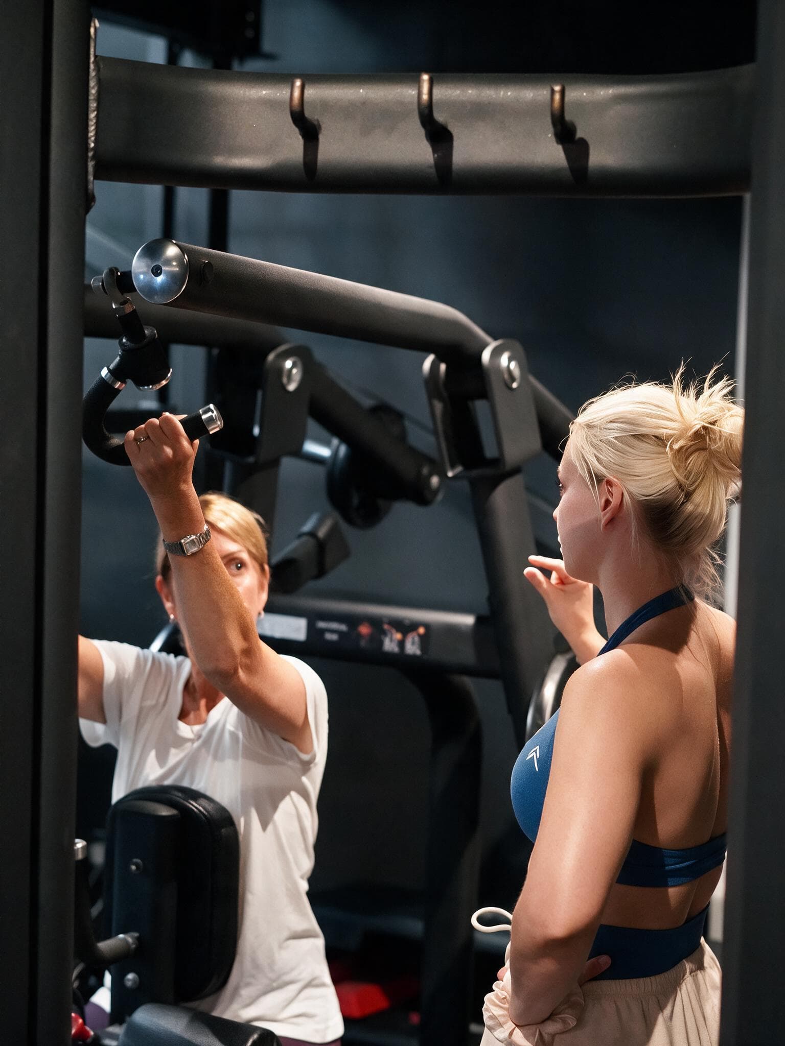 Beth watching a client's form as she reaches for a machine handle